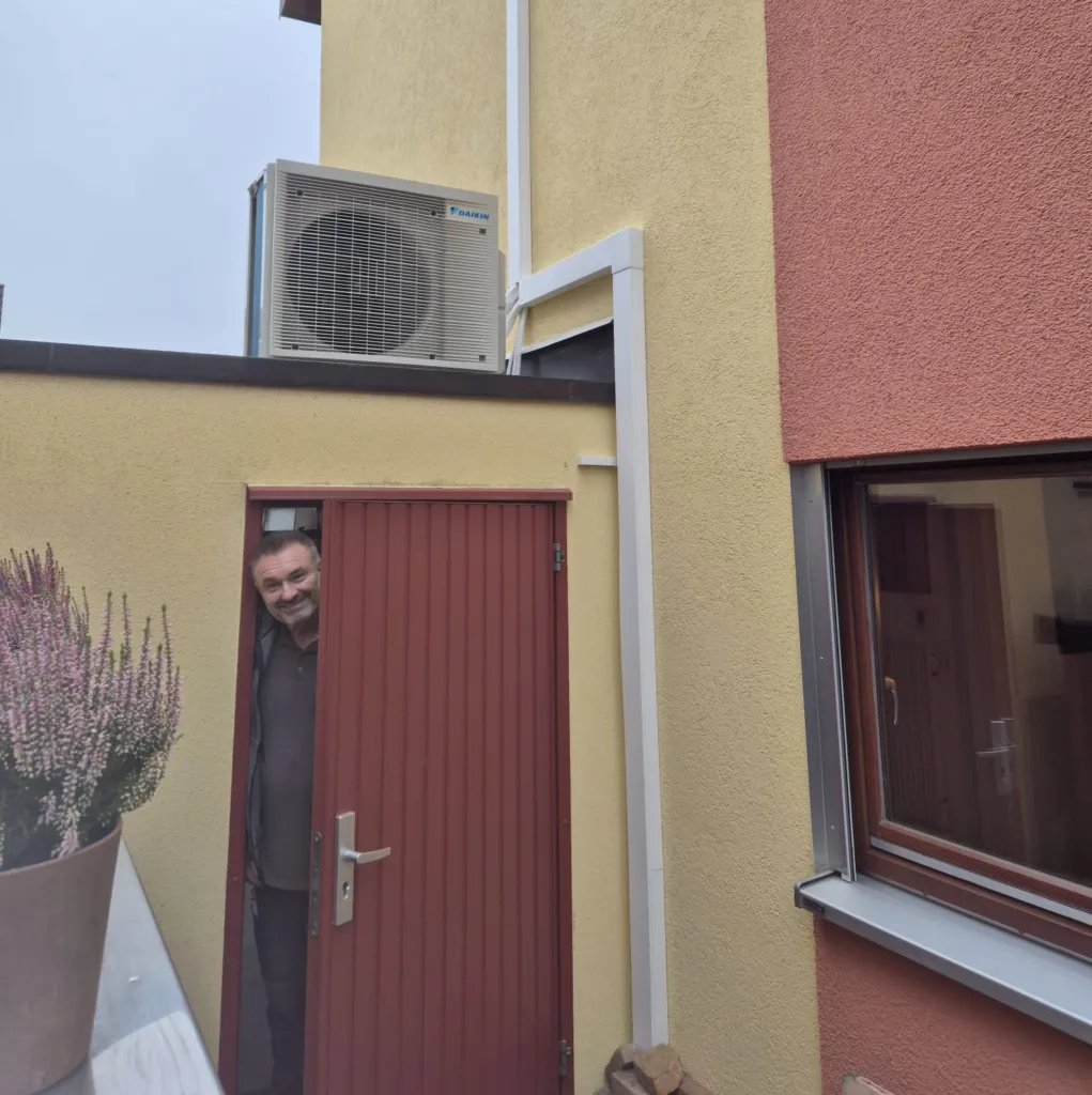 Montiertes Außengerät auf dem Flachdach eines Anbaus, Leitungen im Kabelkanal an der Fassade