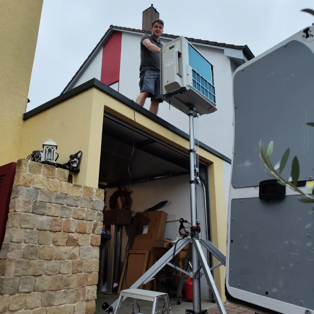 Montage: Ein Außengerät wird mit einem Materiallift auf ein Garagendach gehoben